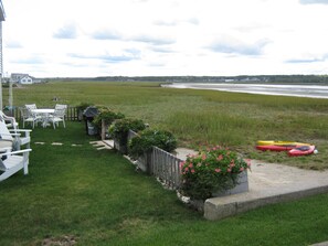 A grassy yard with a patio, chairs, a table, and kayaks. - Last minute discount. Private beach on Harborside . Sleeps 10. Kayaks included (Wells)