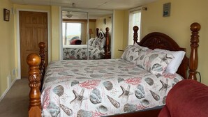 A bedroom with a bed, a mirror, a door, and a window.
