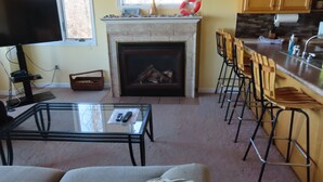 A living room with a fireplace, a television, a glass coffee table, and a sofa.
