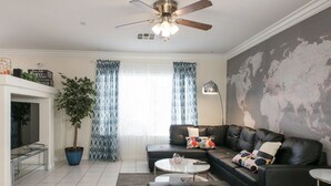 Un salon moderne avec un canapé d’angle, une table basse, un téléviseur et une carte du monde accrochée au mur.