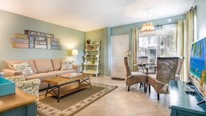 A living room with a sofa, coffee table, and chairs, a bookshelf, and a painting on the wall.