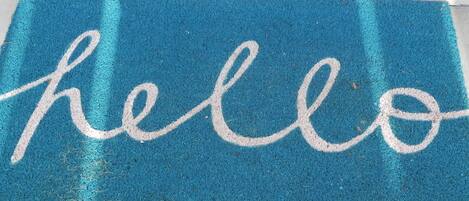 A blue doormat with the word "hello" in white letters.
