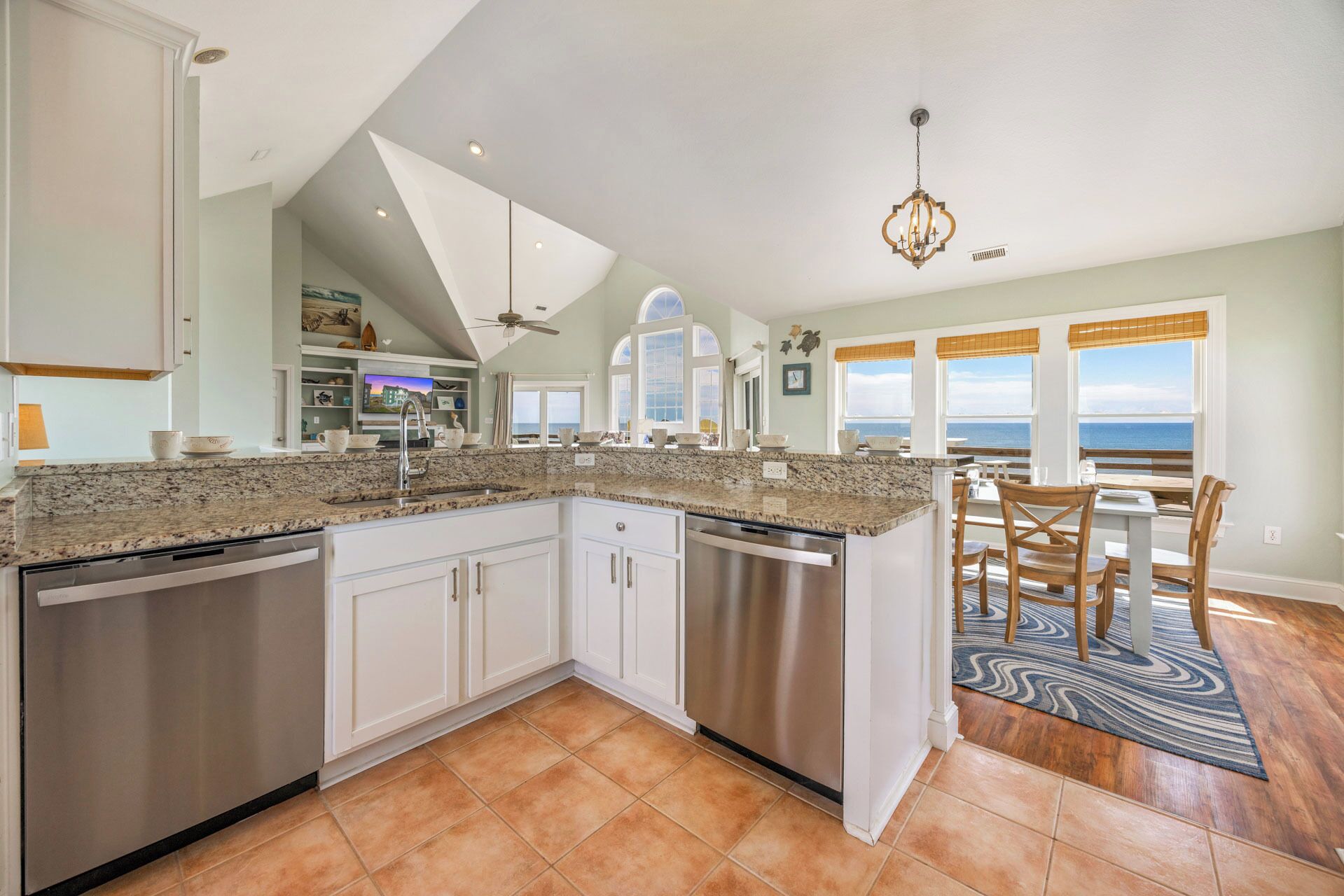 A modern kitchen with a large island, stainless steel appliances, and a dining area with a view of the ocean.