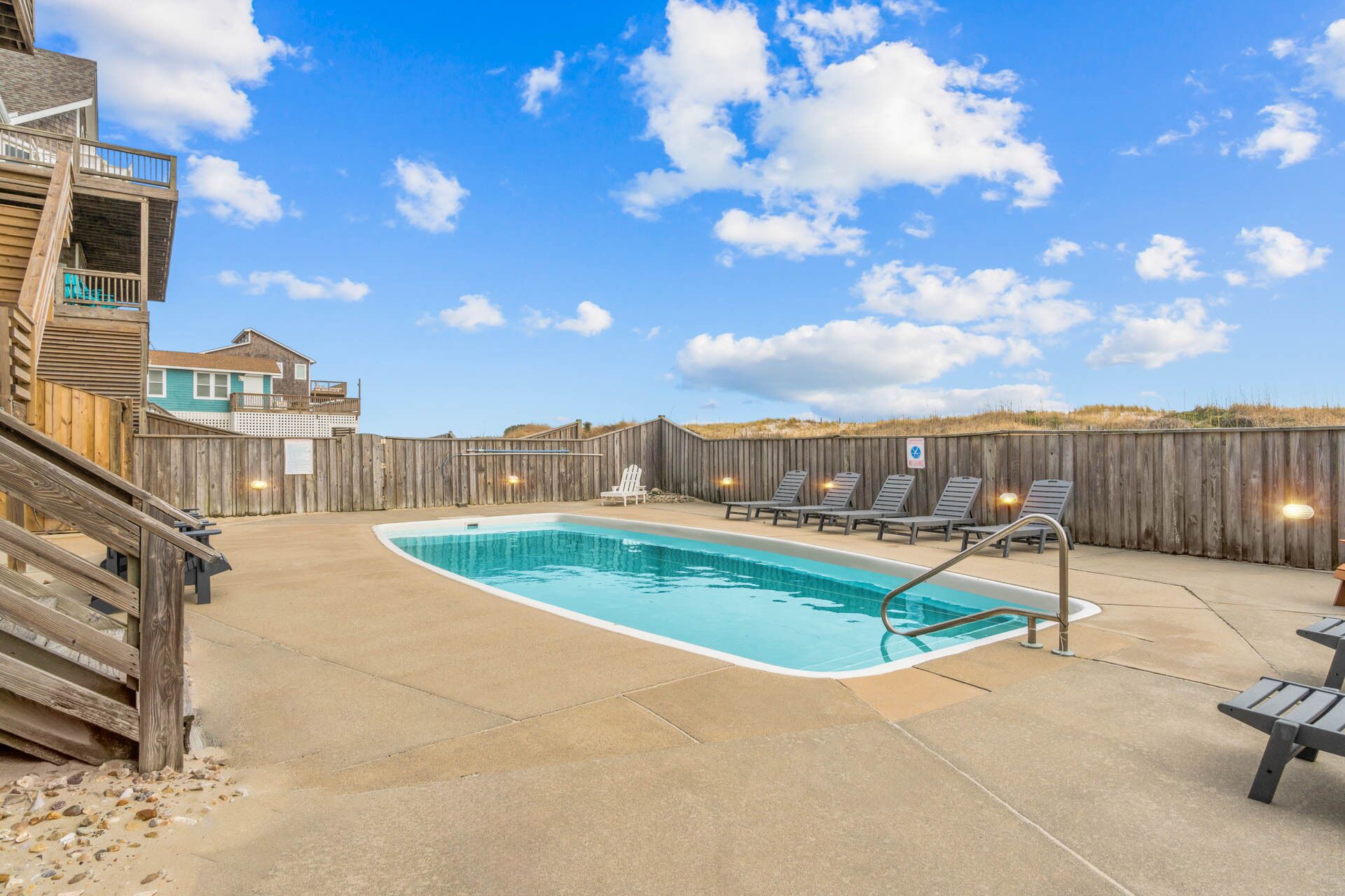 Un jardin avec une piscine, une terrasse en bois et des chaises longues.