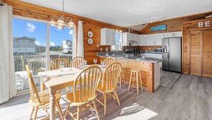 A modern kitchen with wooden accents, a dining area with wooden chairs, and a view of the city.