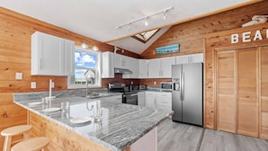 A modern kitchen with granite countertops, stainless steel appliances, and wooden paneling.