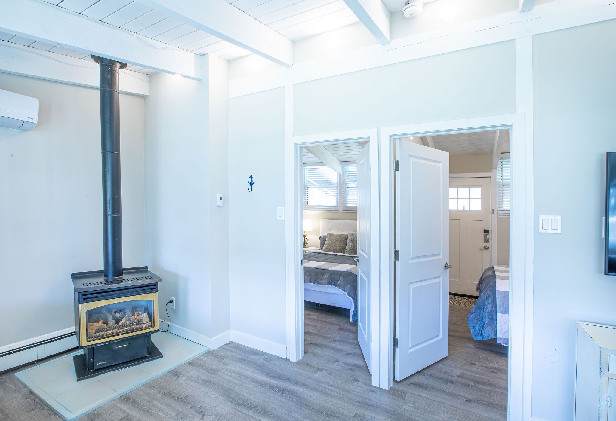 A room with a wood-burning stove, a bed, and a door leading to another room.