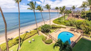 A resort with a pool, beach, and palm trees.