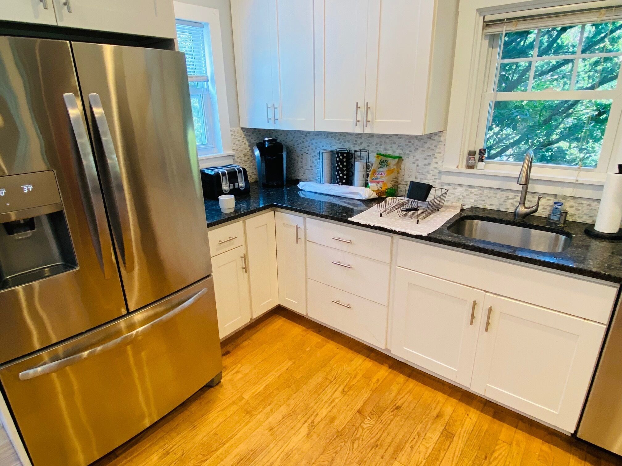 A modern kitchen with stainless steel appliances, white cabinets, and a wooden floor.