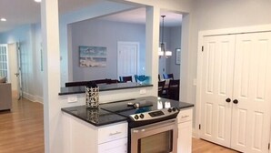 A kitchen with a stainless steel stove, white cabinetry, and a wooden floor.