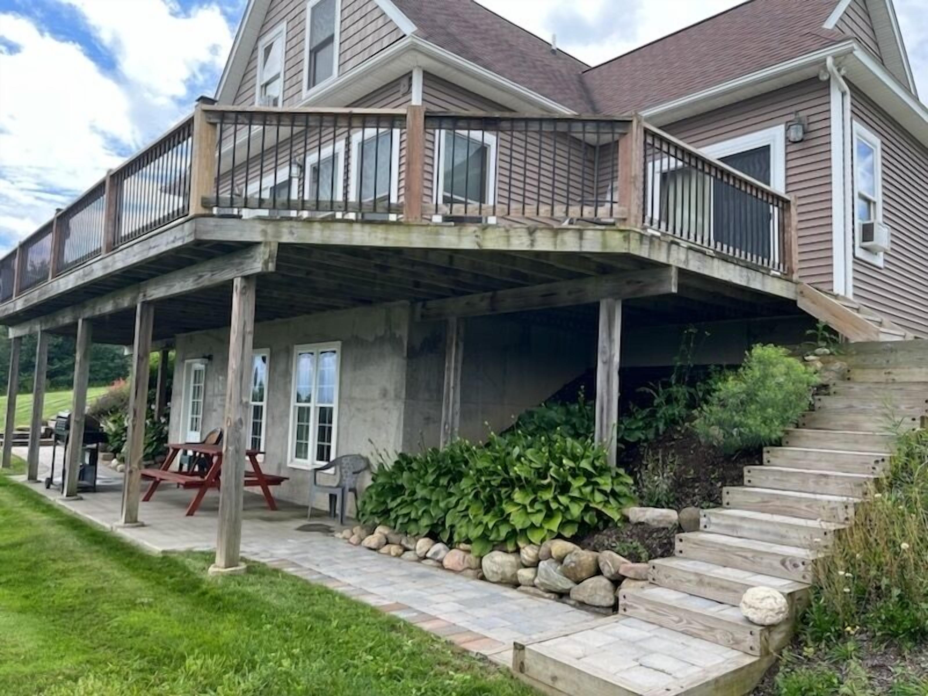 A two-story house with a covered porch, stone steps, and outdoor seating.