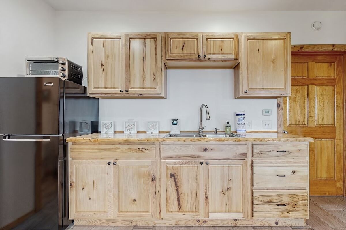 A kitchen with wooden cabinets, a stainless steel refrigerator, and a built-in oven.