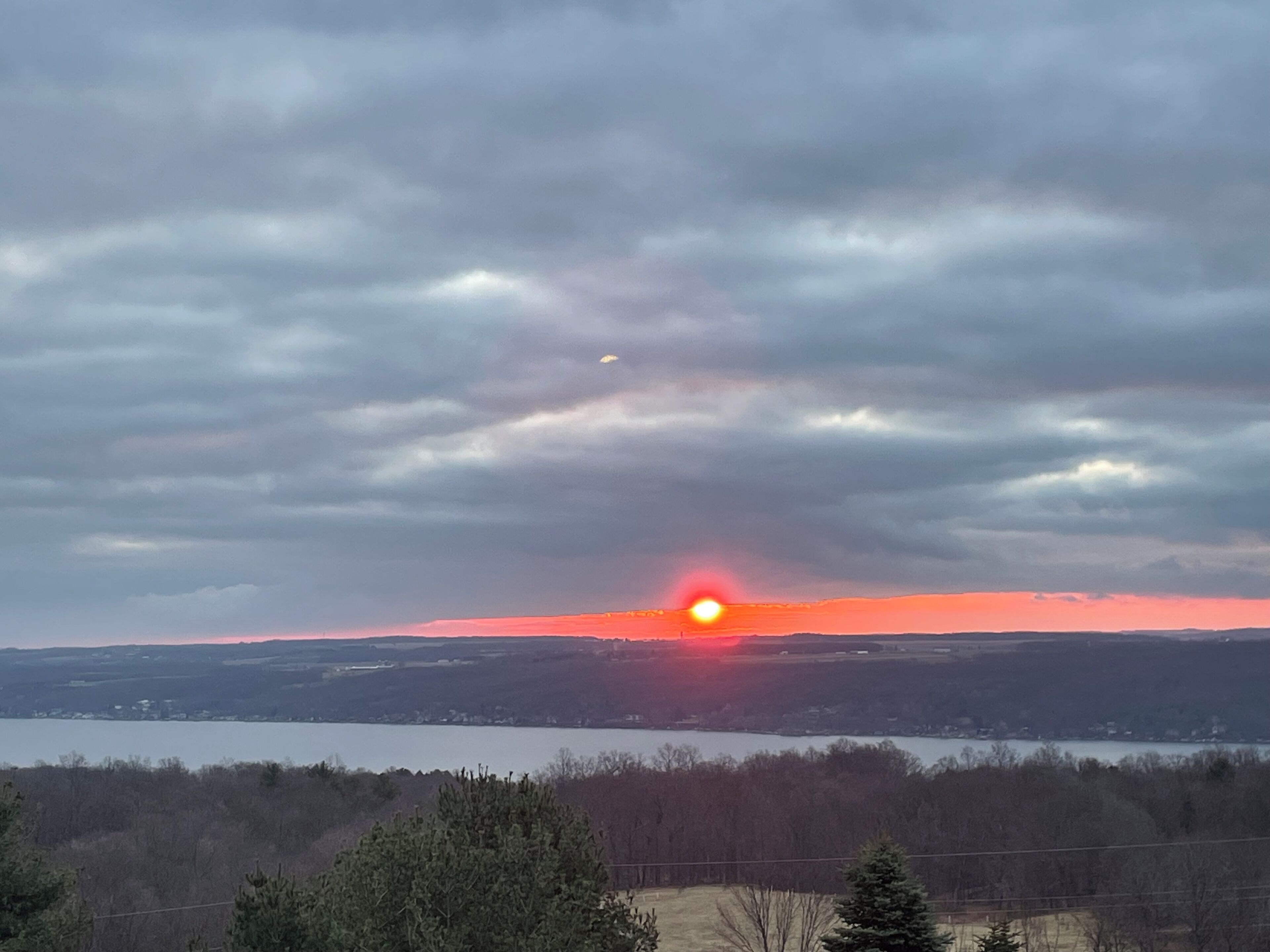 A sunset over a lake with a cloudy sky.