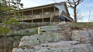 A two-story building with a balcony, situated on a rocky hillside. - Calico Rock Cabin-406 Calico St 302 Chessmond Ferry Rd viewing the White River (Calico Rock)