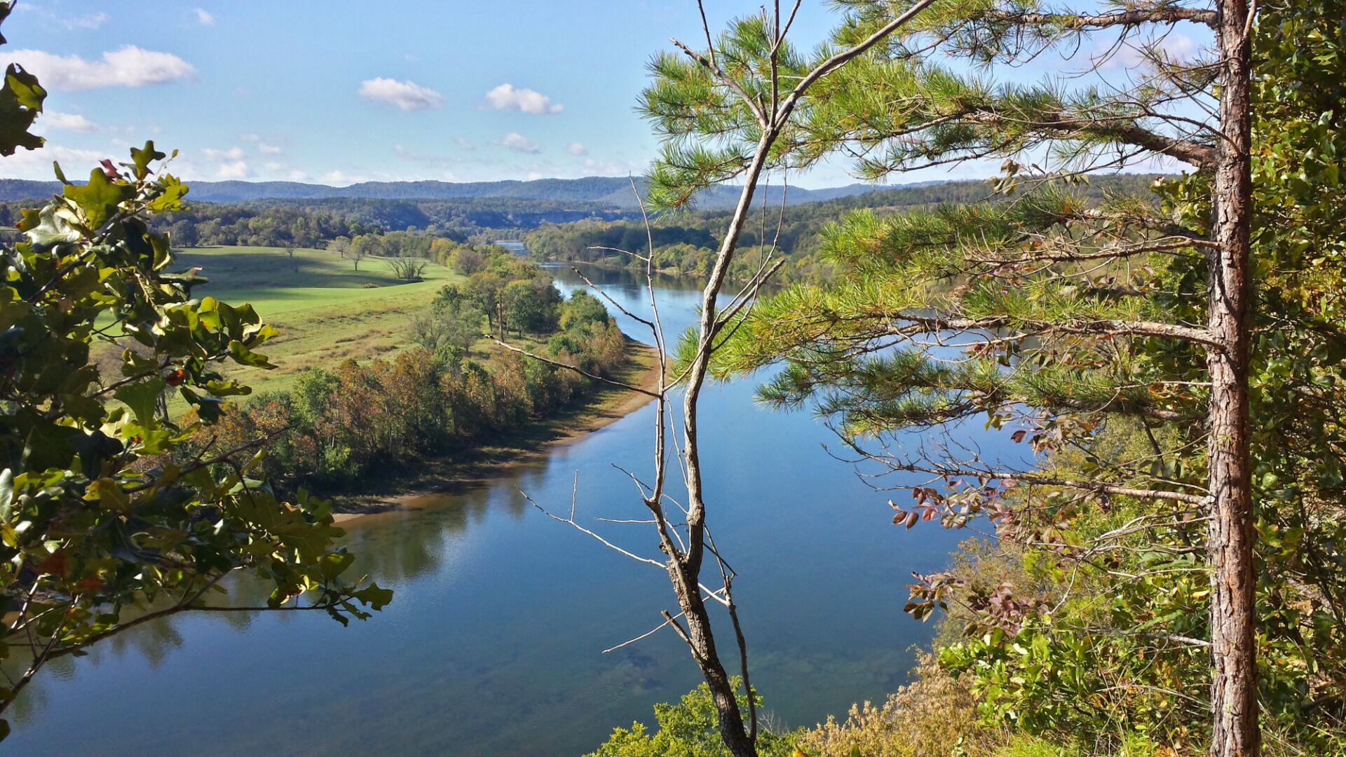 A river valley with a clear view of the surrounding landscape, including hills and trees.