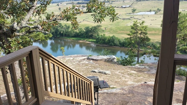 A wooden deck with a view of a lake, surrounded by trees and open fields. - Calico Rock Cabin-406 Calico St 302 Chessmond Ferry Rd viewing the White River (Calico Rock)