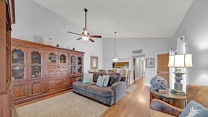 A spacious living room with a wooden cabinet, a grey sofa, and a wooden coffee table.