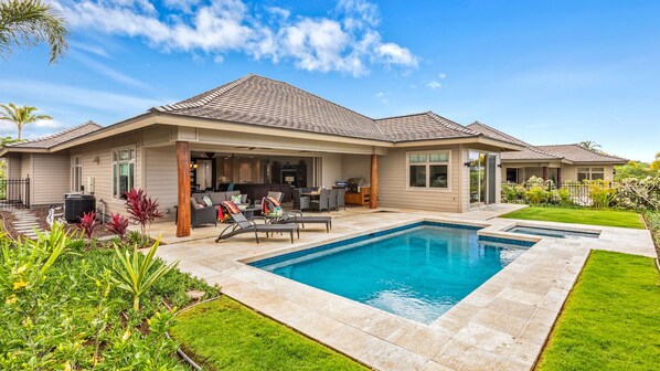 Uma casa de dois andares com piscina, área de estar ao ar livre e um jardim bem cuidado.