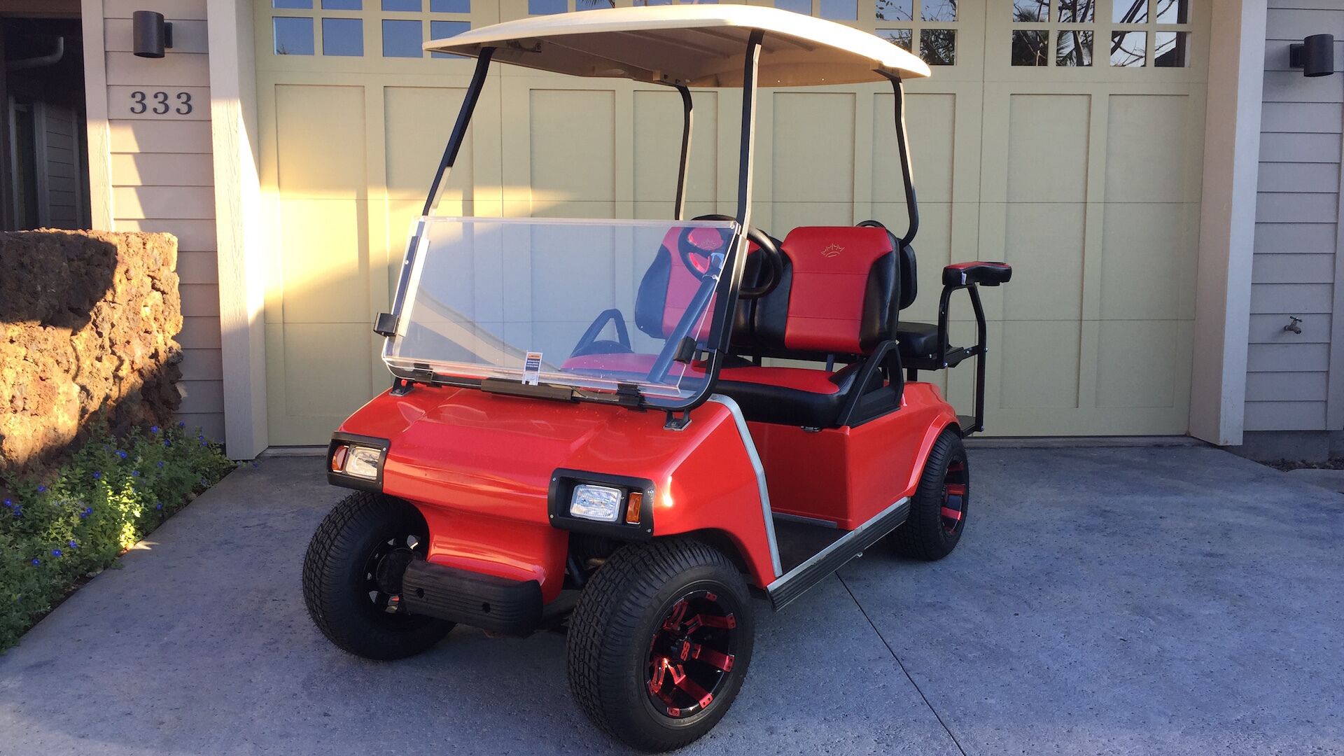 A red golf cart parked in front of a building with a garage door marked with the number 333.
