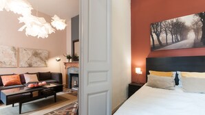 Quarto de hotel com cama, sofá, lareira e um quadro na parede.