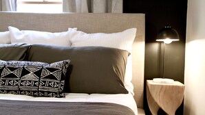 Un letto rifatto con cura, cuscini decorati, una lampada da comodino e vista sulla finestra con tende.