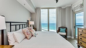 A bedroom with a large bed, a nightstand, a chair, and a dresser.