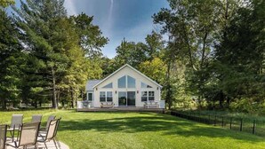 A house with a large front porch, surrounded by a well-maintained lawn and trees. - Vast Open Floor Home with Fire Pit on the Lake (Pullman)