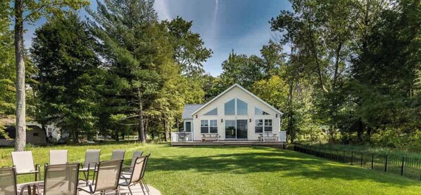 A house with a large front porch, surrounded by a well-maintained lawn and trees.