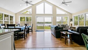 A spacious living area with a high ceiling, large windows, and a view of the outdoors. - Vast Open Floor Home with Fire Pit on the Lake (Pullman)