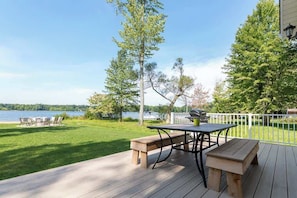 A deck with a table and benches overlooking a lake.