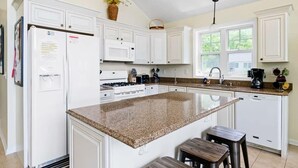 A kitchen with white cabinets, a granite countertop, a stove, a sink, and a window. - Vast Open Floor Home with Fire Pit on the Lake (Pullman)