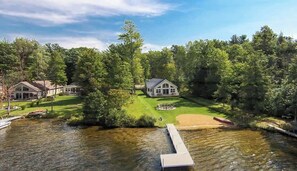 A lakeside property with a large house, a dock, and a well-maintained lawn.