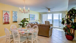 A dining area with a table set for four, a sofa, and a large plant. - Wind Drift 603SE
Gulf Front
RECENT CANCELATION!!!
BOOK NOW! (Orange Beach)