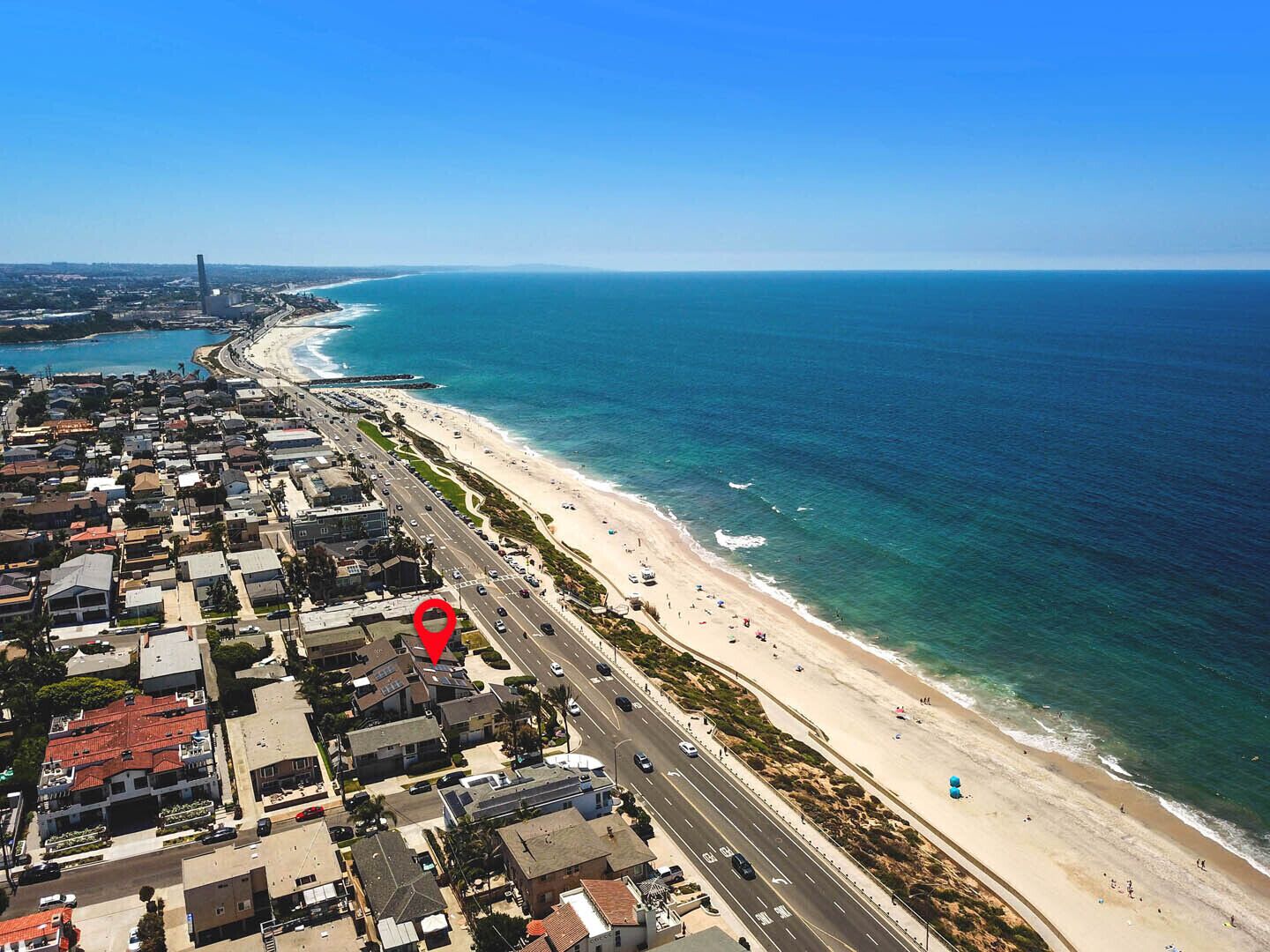 Vue aérienne d’une ville côtière avec une plage, des routes et des immeubles d’habitation.