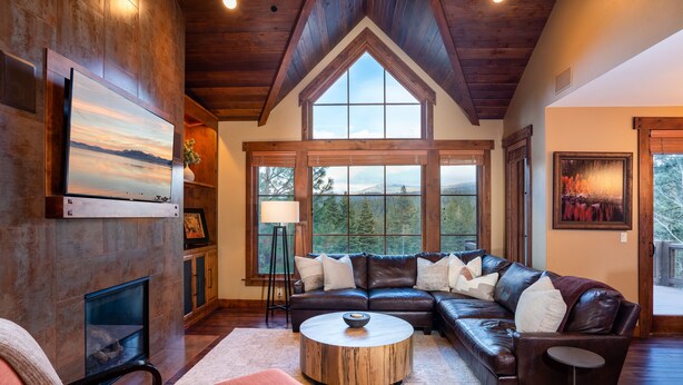 Amplia sala de estar con un sofá seccional grande, una chimenea y ventanas amplias que ofrecen vistas al exterior.