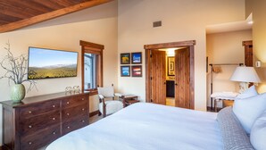 Un dormitorio con una cama grande, un aparador de madera y un escritorio con una silla. Hay cuadros enmarcados en la pared y una ventana con vistas al paisaje.