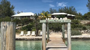 Eine Holzstege führt zu einem Strandabschnitt mit klarem, türkisblauem Wasser, einem Schild mit der Aufschrift „Banyue Island Resort“ und einem weißen Gebäude im Hintergrund.