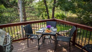 Une terrasse en bois avec une table et des chaises, entourée d’une balustrade en bois.