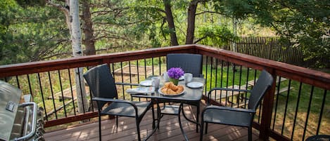 A wooden deck with a table and chairs, surrounded by a wooden railing.