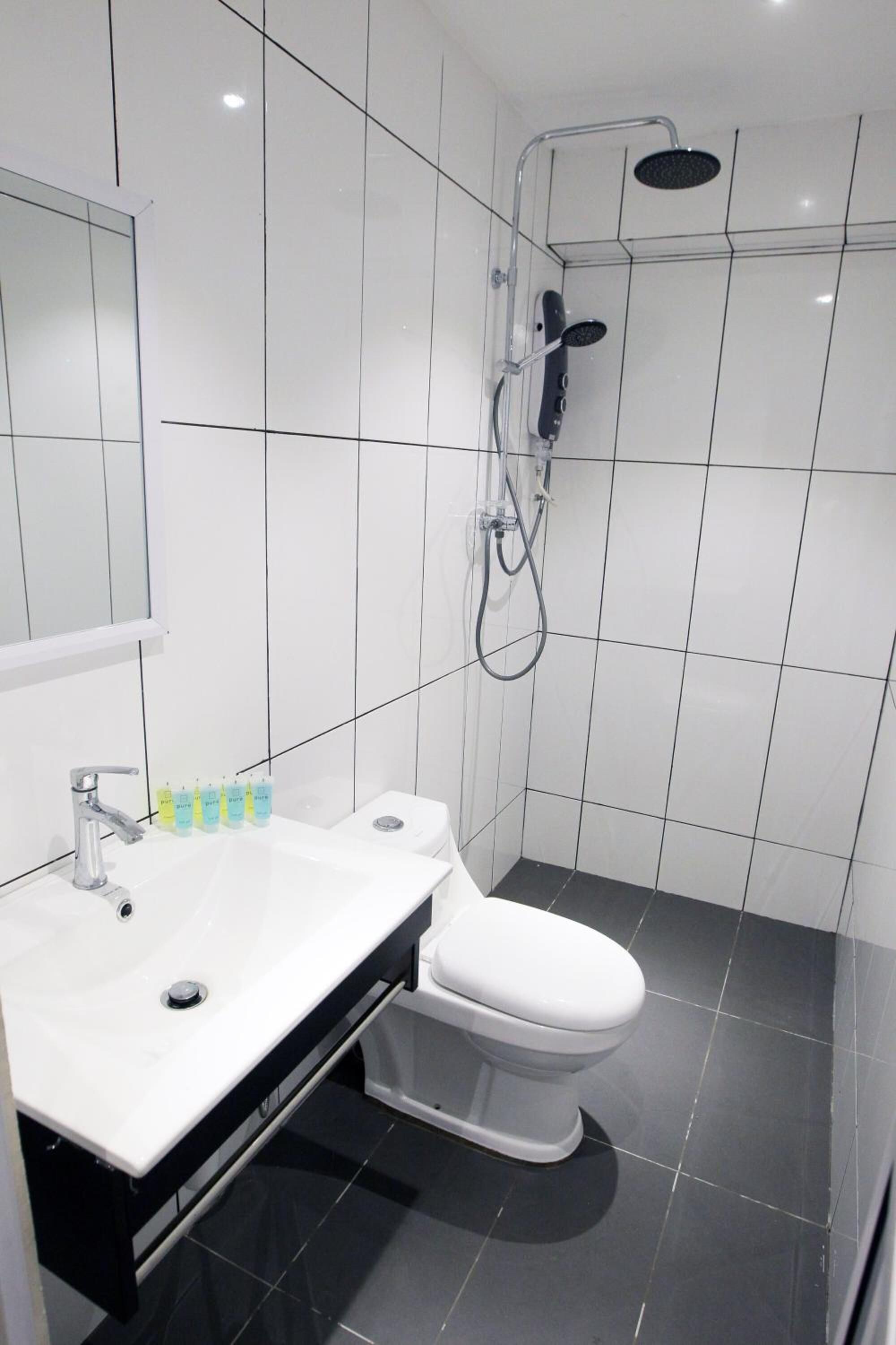 Et moderne badeværelse med en hvid vask, toilet og bruseområde.