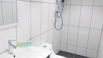Et moderne badeværelse med en hvid vask, toilet og bruseområde.