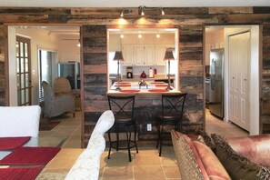 Una sala de estar acogedora con chimenea, un comedor con barra y una cocina visible a través de un umbral abierto.