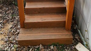 Un escalier en bois, doté d’une rampe, mène à l’entrée d’un bâtiment.