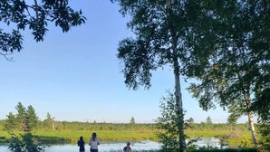A lakeside campsite with a fire pit, trees, and a clear sky.