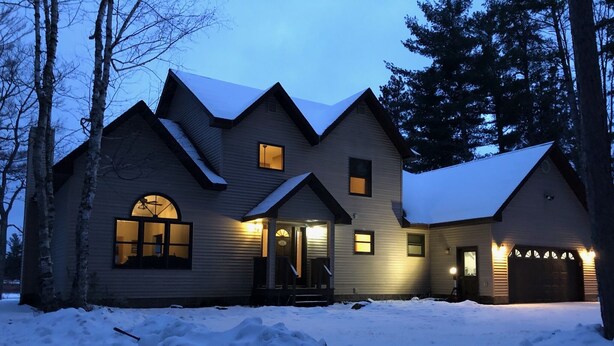 A large, multi-story house with a steeply pitched roof, multiple windows, and a garage.