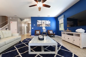 Uma sala de estar moderna com um sofá branco, uma mesa de centro e uma parede azul de destaque.