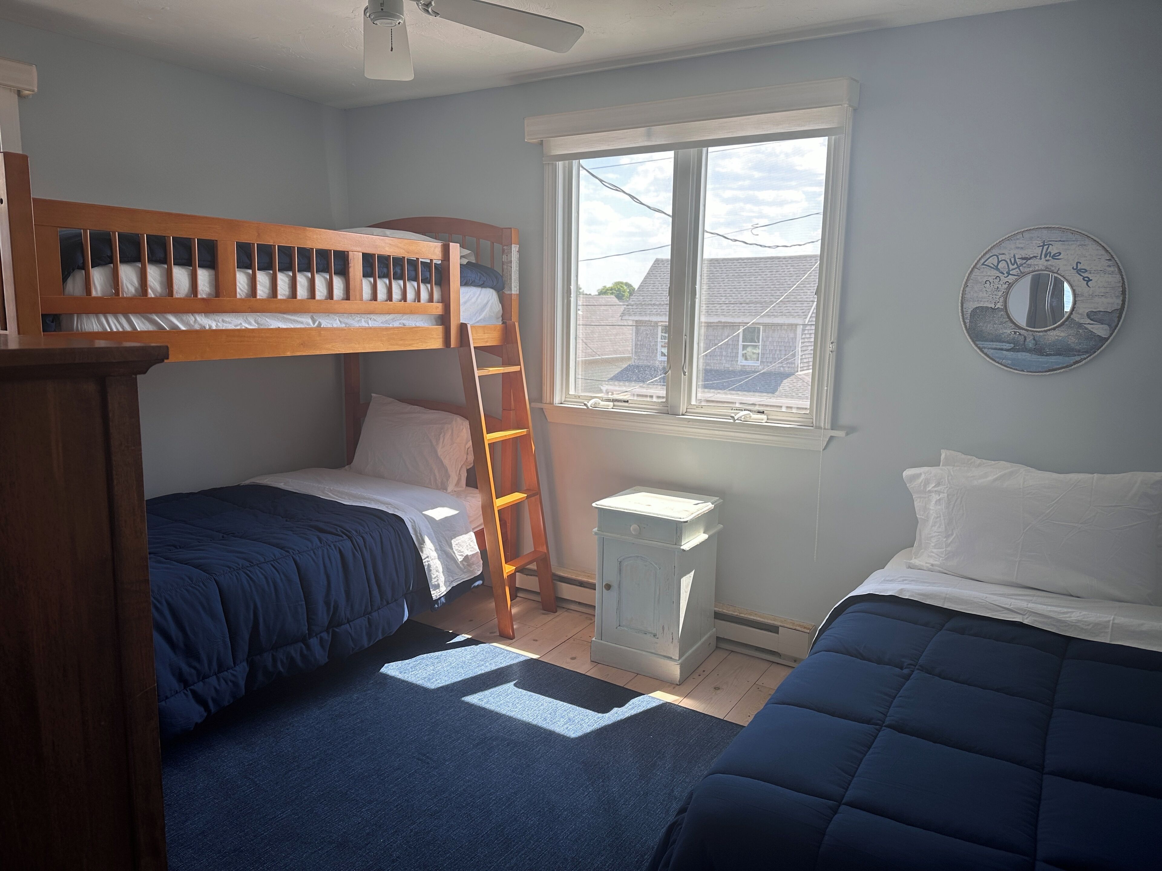 Een kamer met stapelbedden, een raam met uitzicht, een plafondventilator en een spiegel aan de muur.