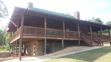 A wooden cabin with a covered porch and a stone foundation.