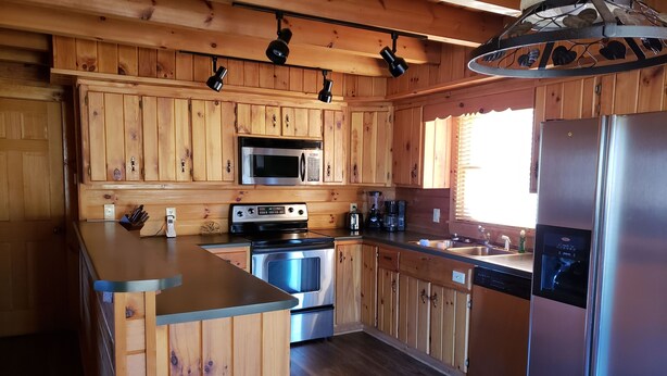 Una cocina con armarios de madera, un refrigerador de acero inoxidable, un microondas, un horno y un fregadero.