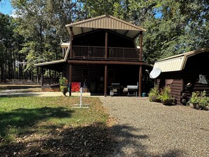 A two-story log cabin with a balcony, a barbecue area, and a satellite dish. - Riverwalk ~ on the lower mountain fork river (Broken Bow)